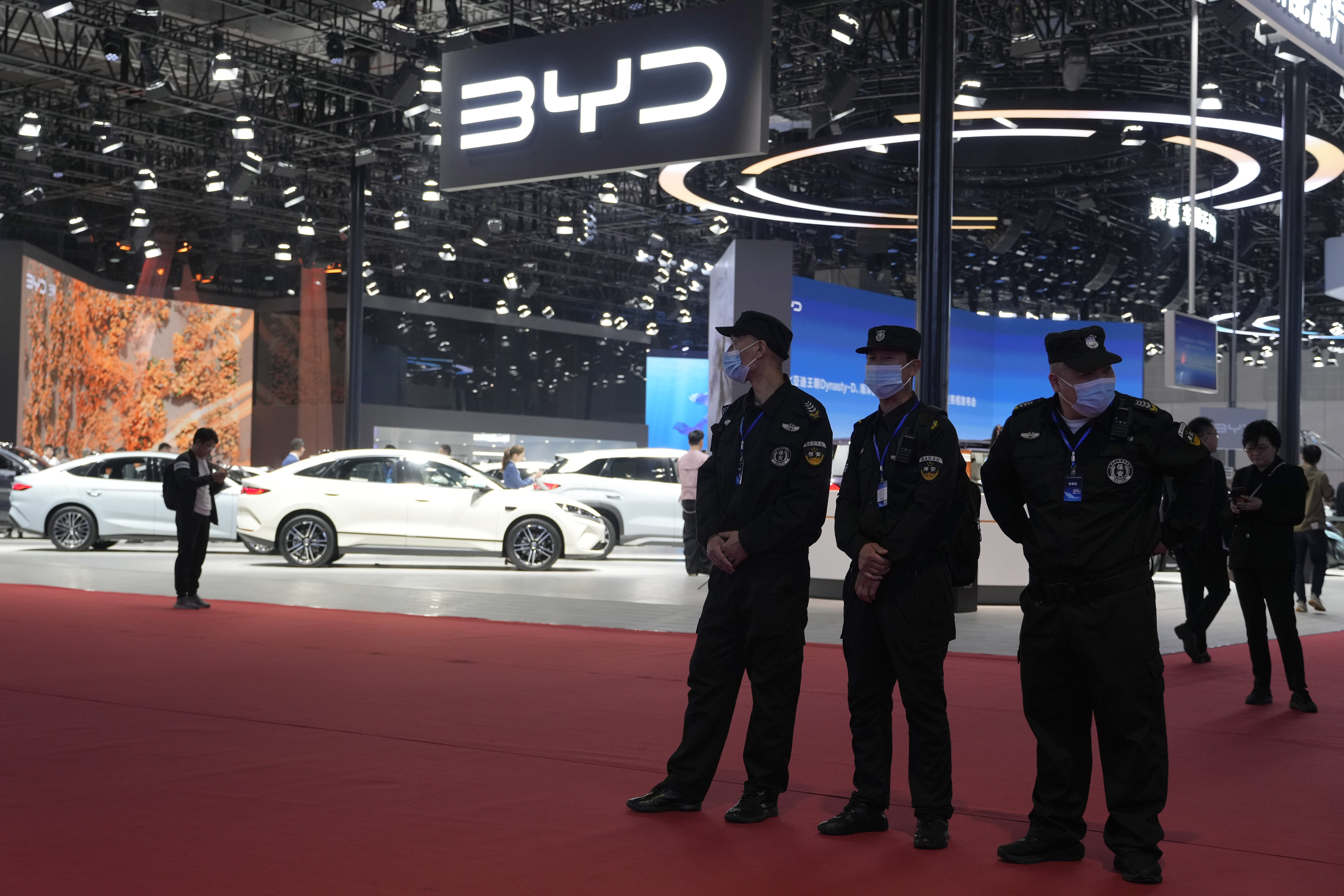 Security personnel on duty stand near the BYD booth during the Shanghai auto show, April 23, 2025.