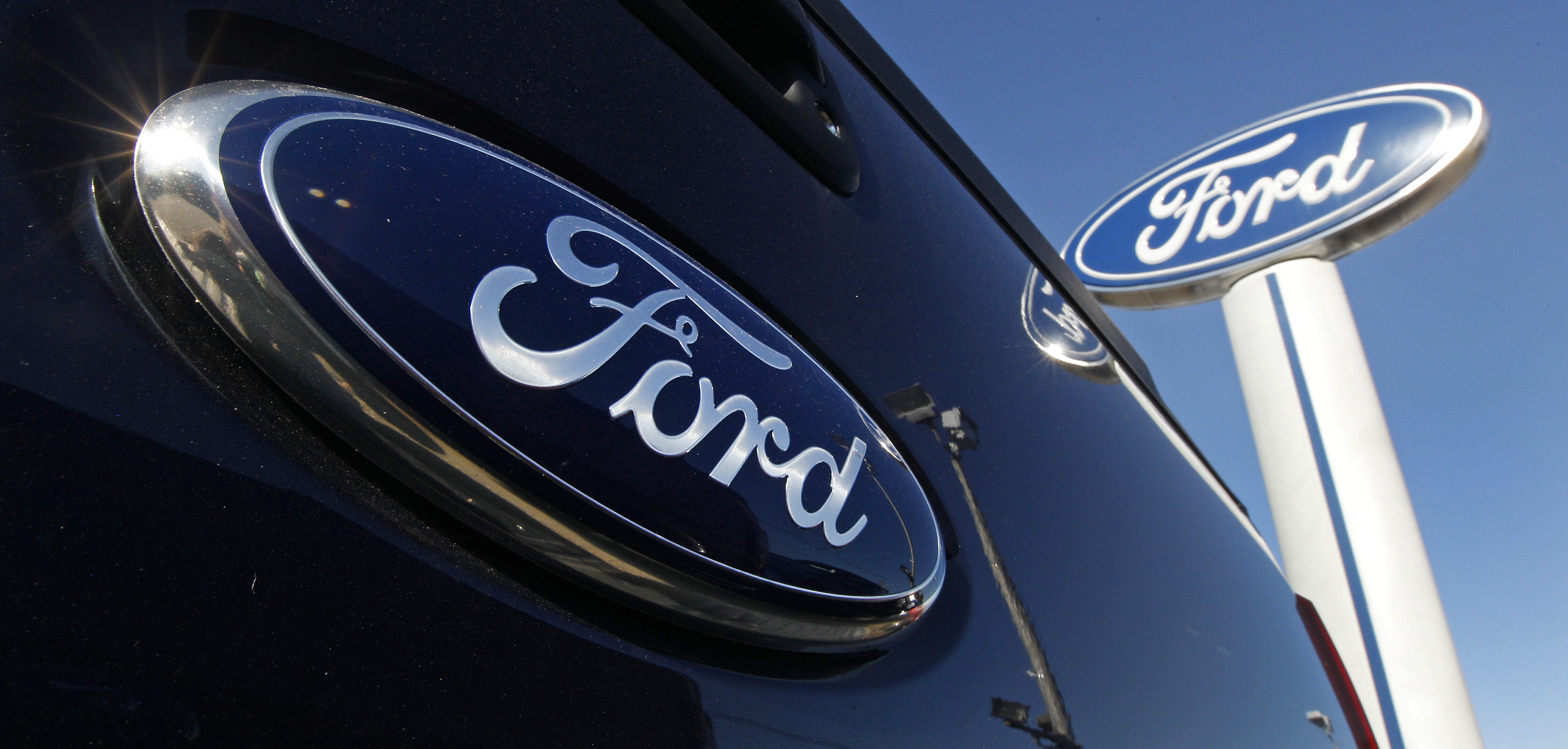 A Ford logo is on the tailgate of a pick-up truck and on a Ford dealership sign in Salem, N.H.