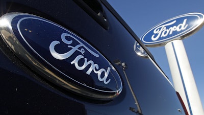 A Ford logo is on the tailgate of a pick-up truck and on a Ford dealership sign in Salem, N.H.