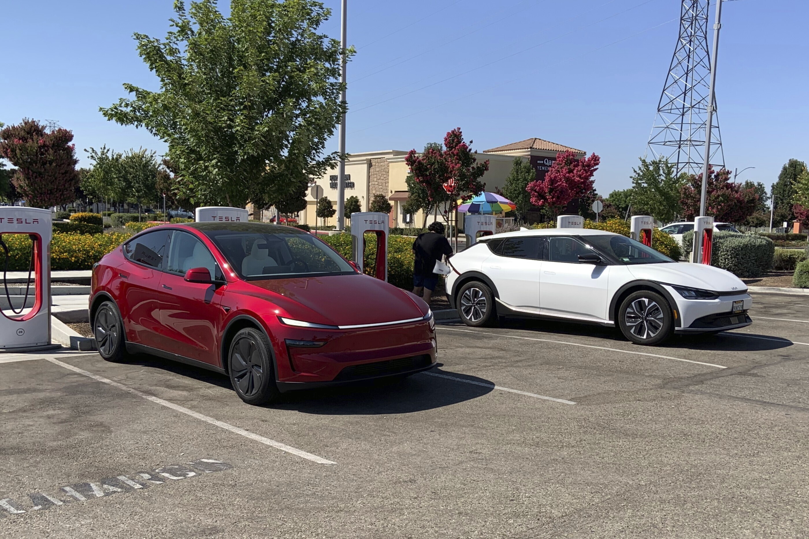 This photo provided by Edmunds shows a Tesla Model Y and a Kia EV6 parked at a Tesla Supercharger station in Fresno, Calif. Planning a cross-country trip in an EV takes extra effort, but doing it properly can make the journey almost as smooth as in a gas-powered vehicle.