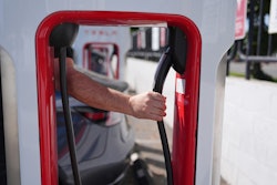 A person reaches to plug in an electric vehicle at a charging station May 22, 2025, in the City of Commerce, Calif.