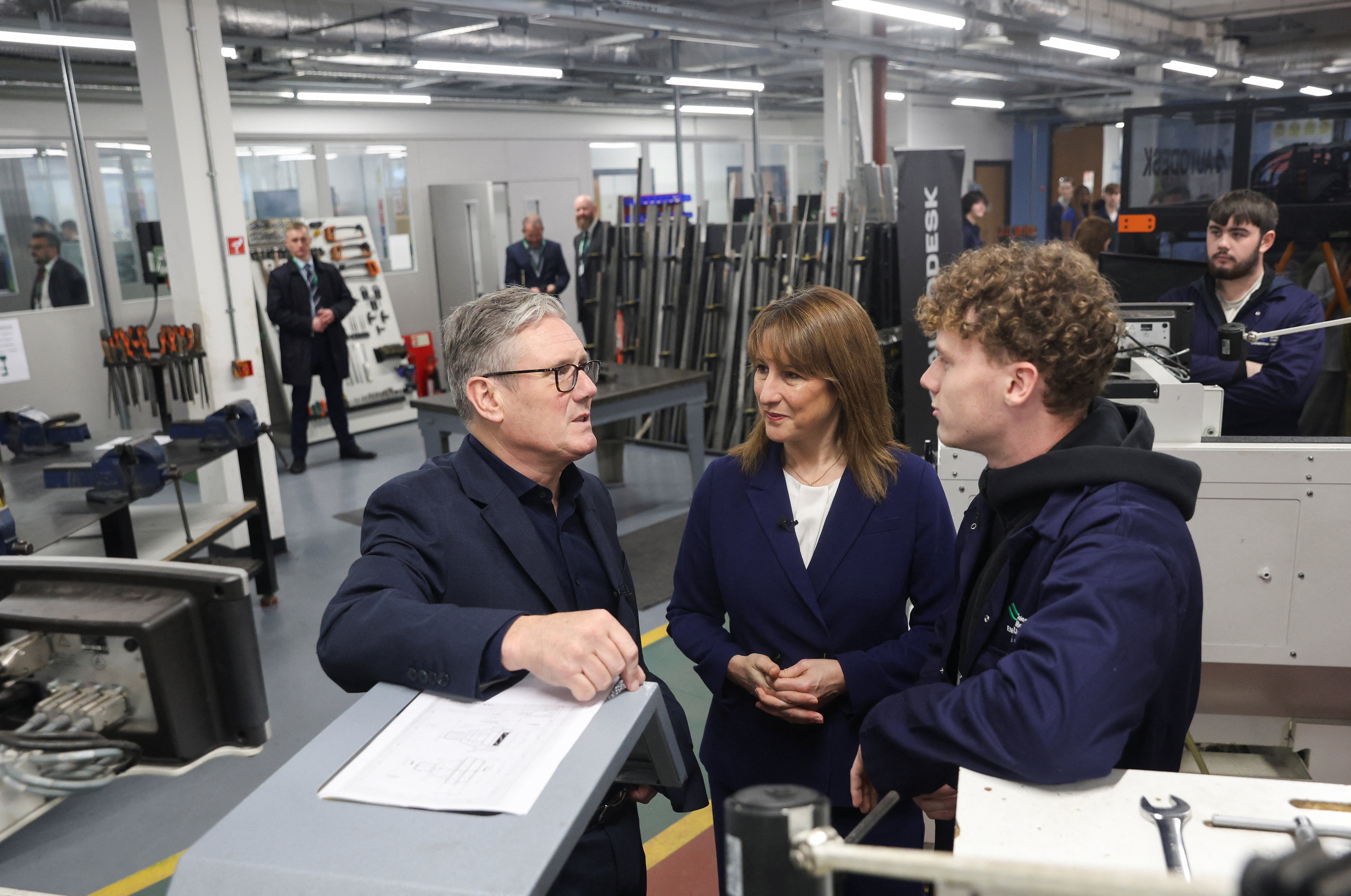 Britain's Prime Minister Keir Starmer, left, talks with a student, next to Britain's Chancellor of the Exchequer, Rachel Reeves, center, at the engineering workshop at Coleg Menai.