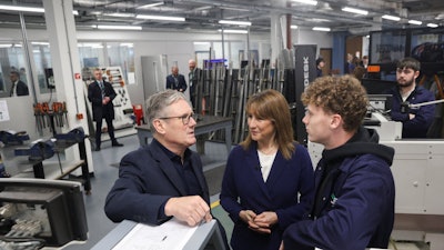 Britain's Prime Minister Keir Starmer, left, talks with a student, next to Britain's Chancellor of the Exchequer, Rachel Reeves, center, at the engineering workshop at Coleg Menai.