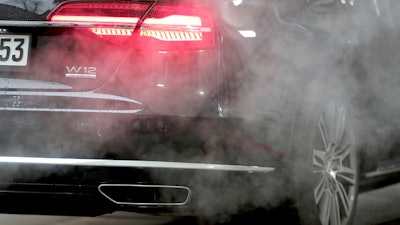 A luxury Audi car is surrounded by exhaust gases as it is parked with a running engine in front of the Chancellery in Berlin, Germany, Wednesday, Nov. 20, 2019.