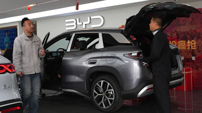 Visitors walk by a hybrid car at a BYD showroom in Beijing, China, Thursday, March 26, 2026.