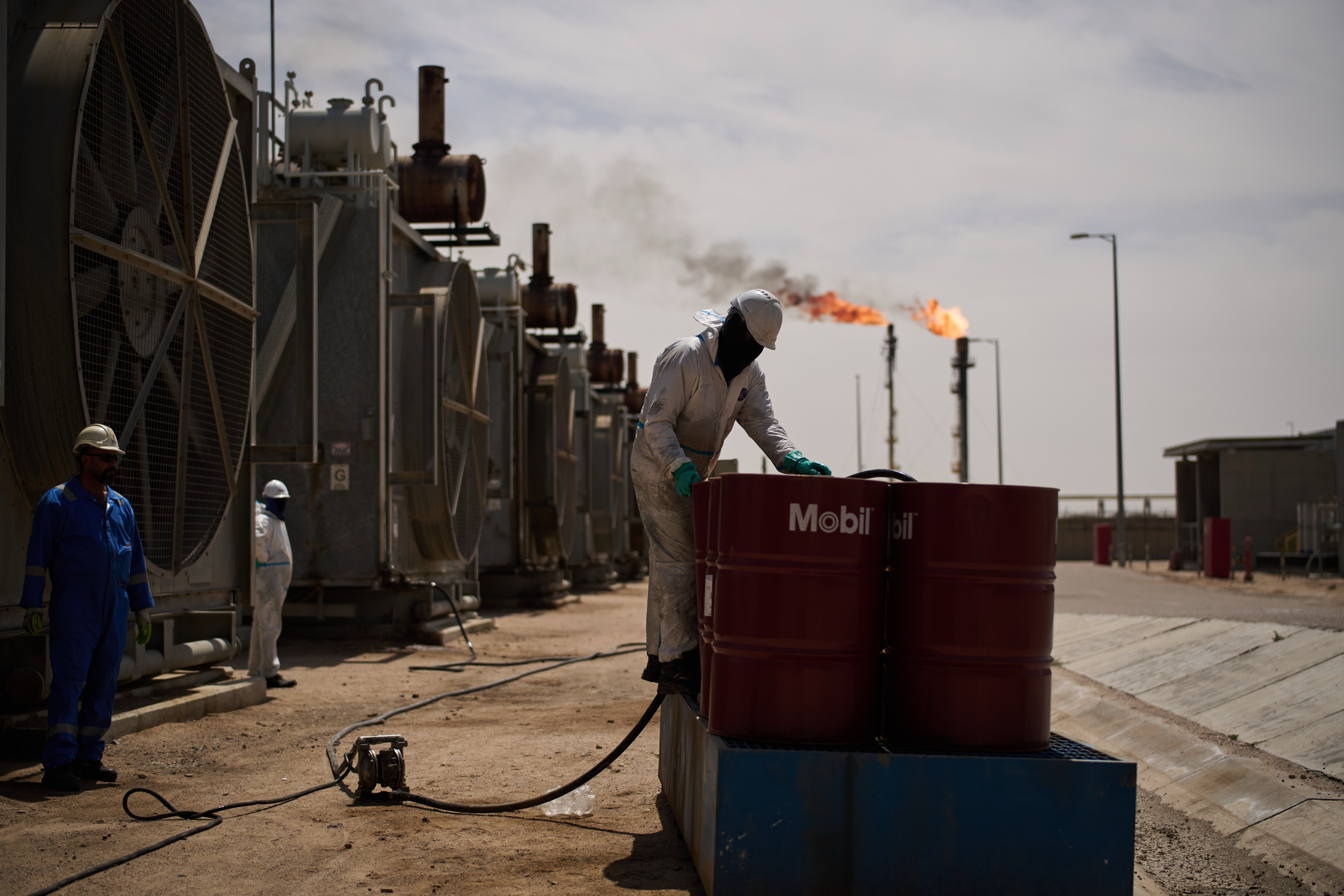 A worker collects engine oil as he works at a degassing station in Zubair oil field, whose operations have being reduced due to the Mideast war triggered by the U.S. and Israeli attacks on Iran, near Basra, Iraq, Saturday, March 28, 2026.