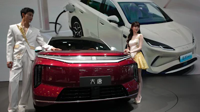Models stand next to a latest EV car from Chinese automaker BYD showcased at the Auto China 2026, in Beijing, April 25, 2026.