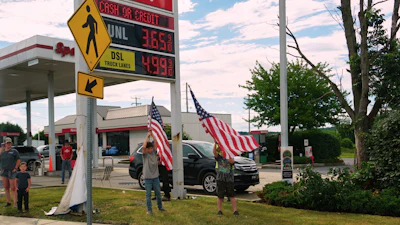 People hold flags in front of a gas station as President Donald Trump's motorcade passes by Tuesday, June 23, 2026, in Pennsylvania.