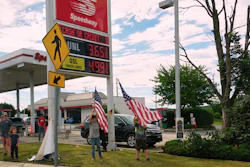 People hold flags in front of a gas station as President Donald Trump's motorcade passes by Tuesday, June 23, 2026, in Pennsylvania.